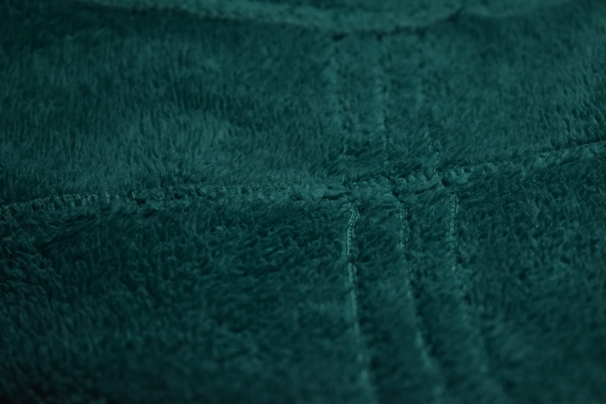 Jahitan dua baris berjalan diagonal di atas bahan fleece berbulu warna teal tua, dilihat dari dekat