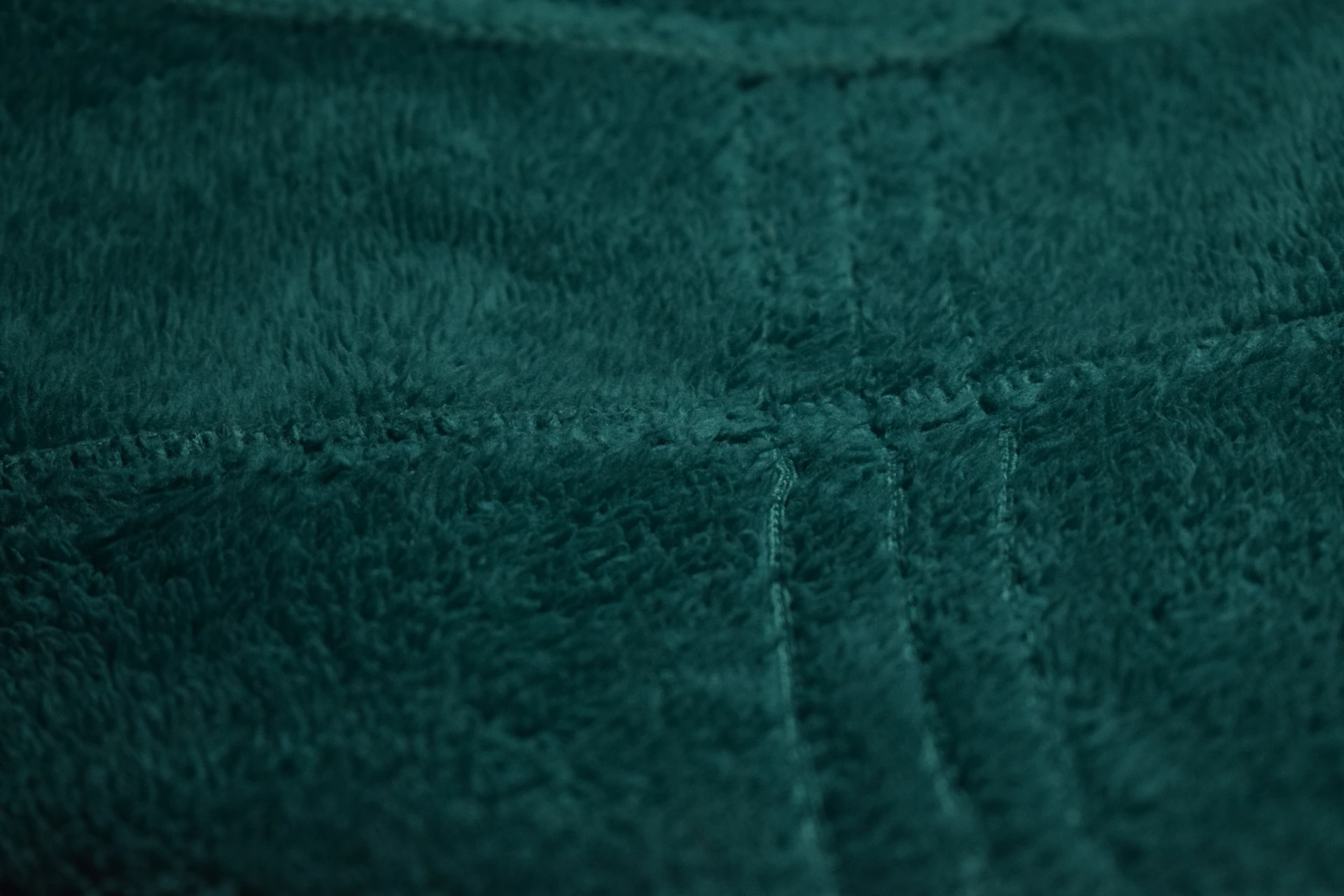 Close-up of dark teal fuzzy fabric with stitching