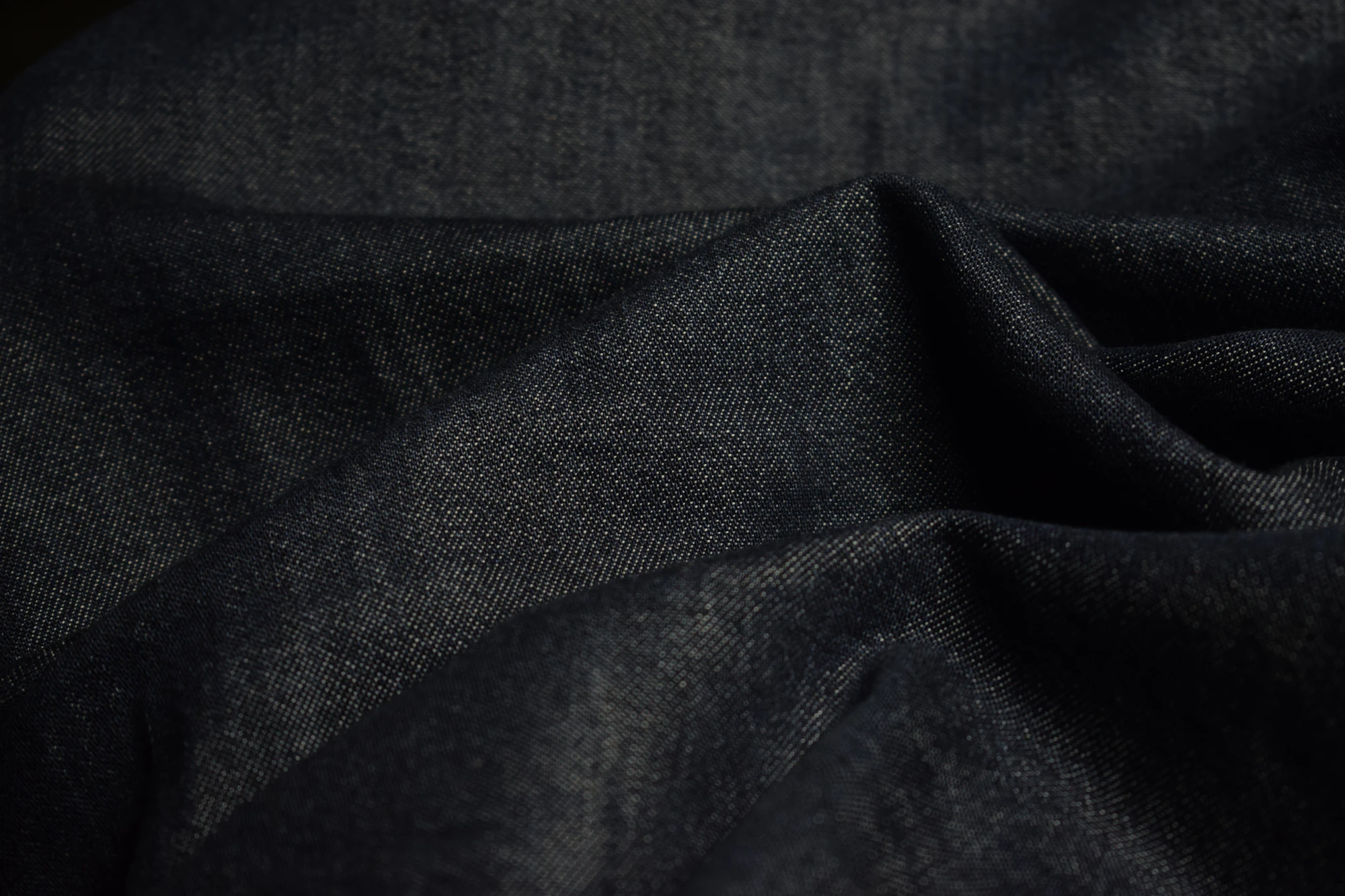 Dark folded vintage cloth in low light, showing soft creases.
