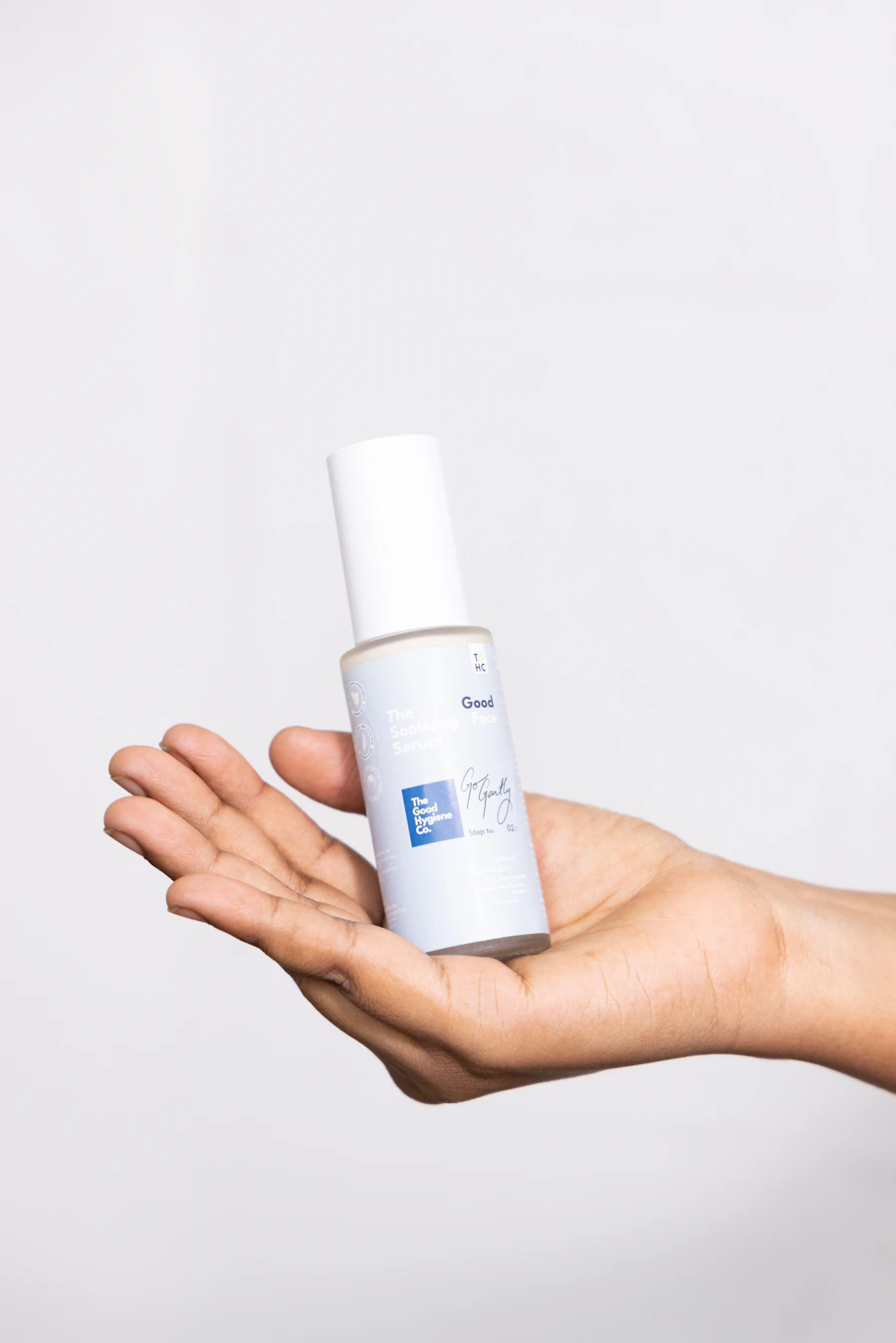Hand holding a white spray bottle of skincare mist