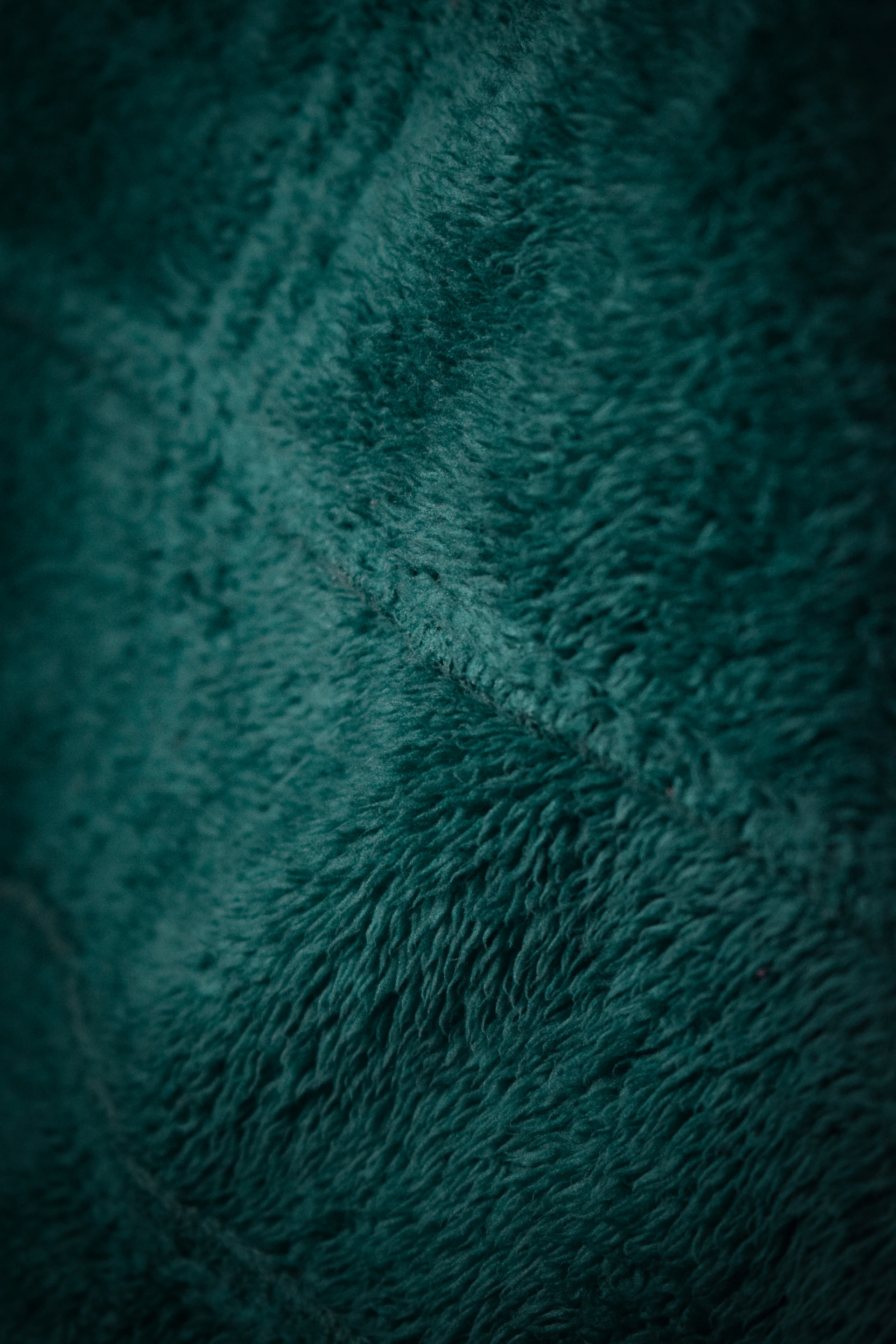 Close-up of a teal fuzzy fabric with a subtle pattern