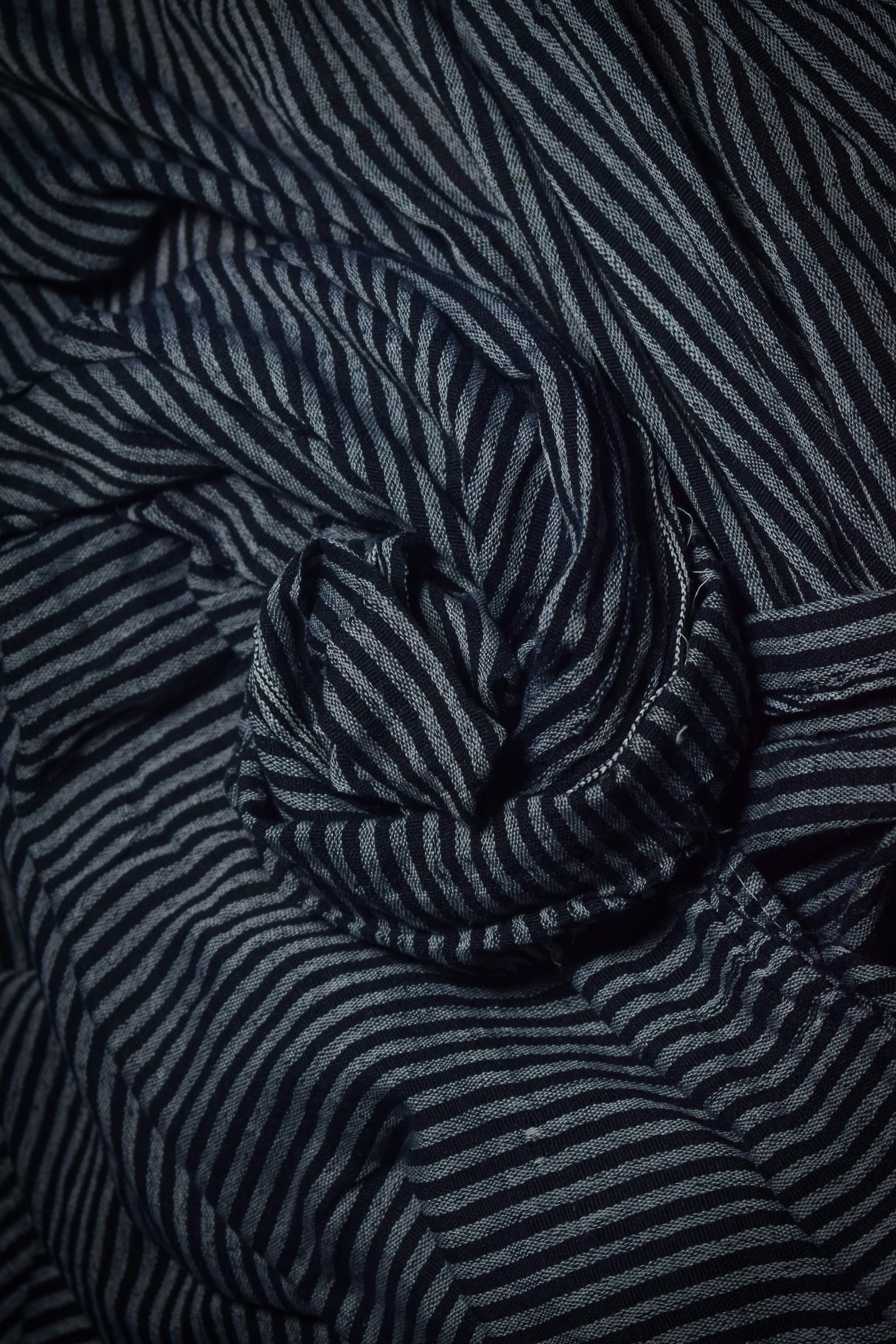 Dark fabric with thin grey stripes folded intricately