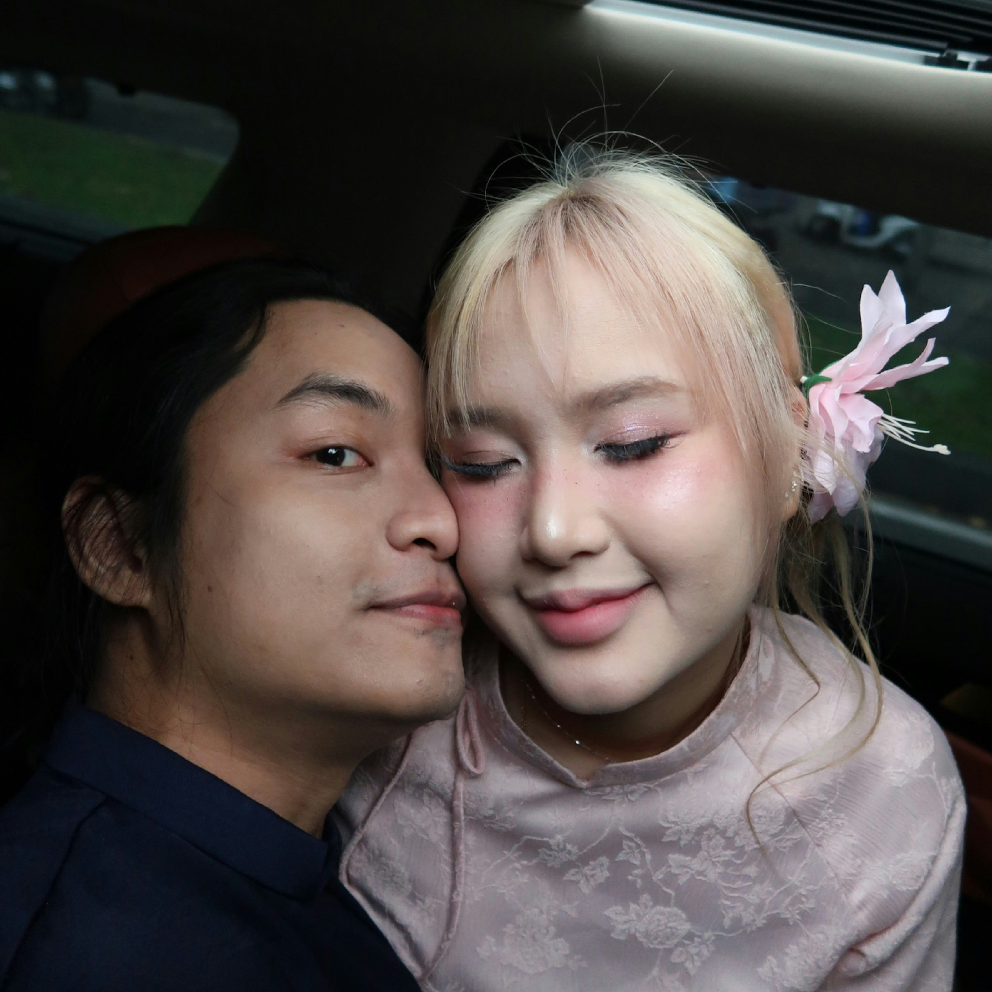 Couple in a car with a flower in her hair.