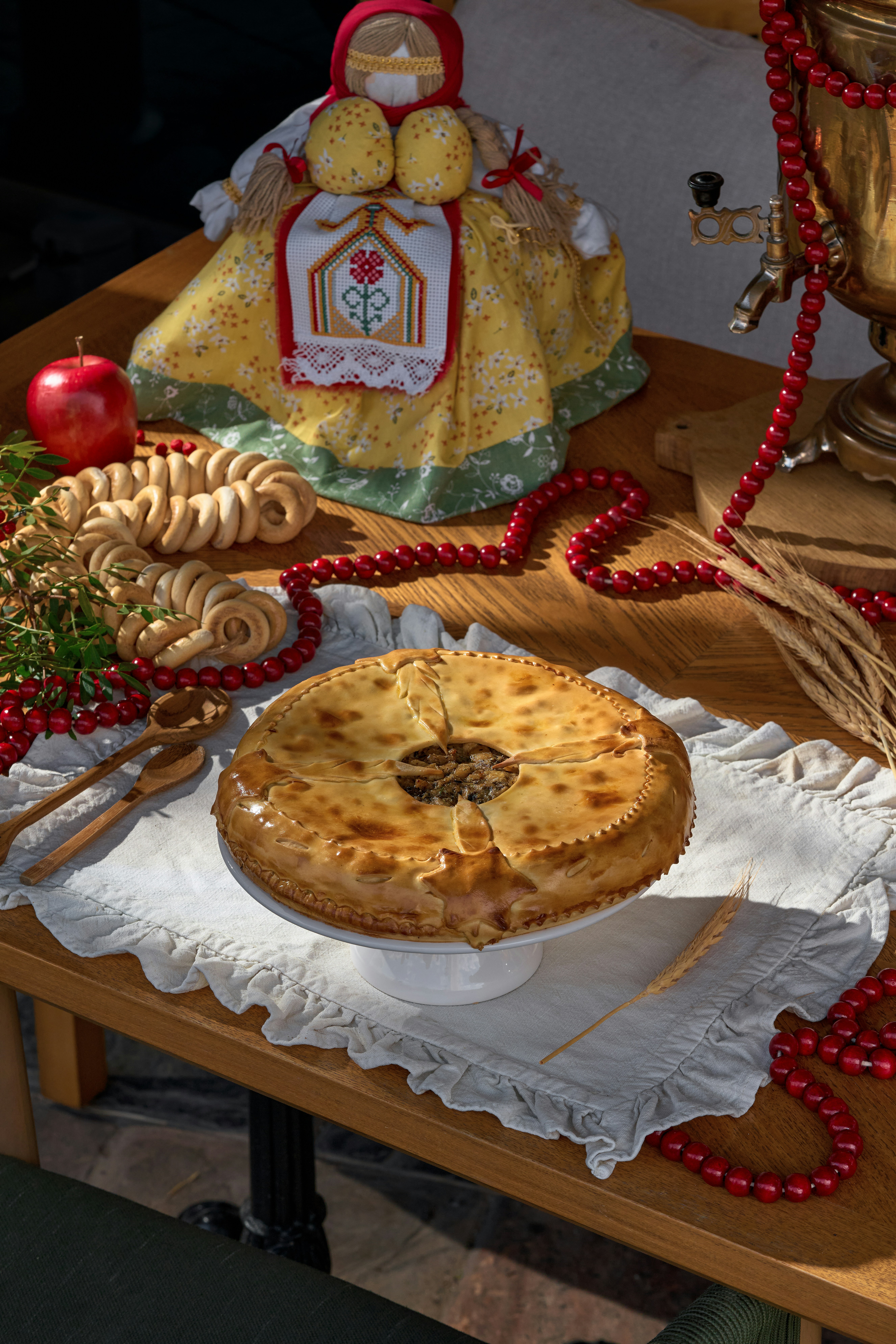 Round pie on a white tablecloth with samovar and doll