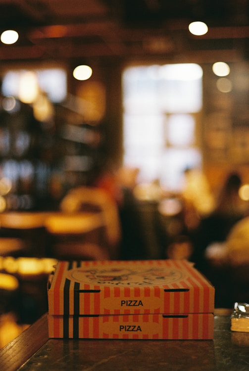 Two pizza boxes stacked on a counter