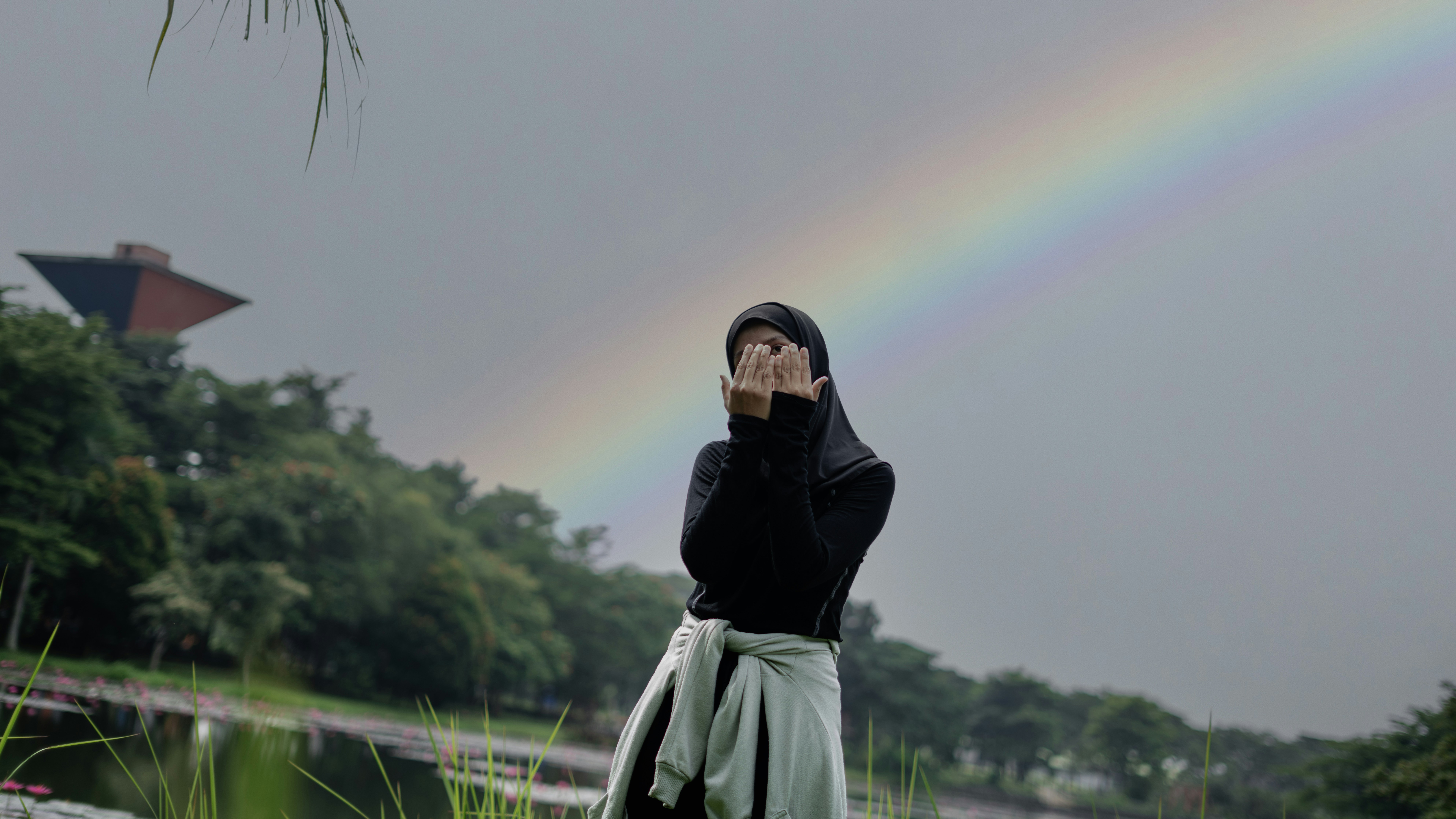 Wanita berjilbab dengan pelangi di belakangnya