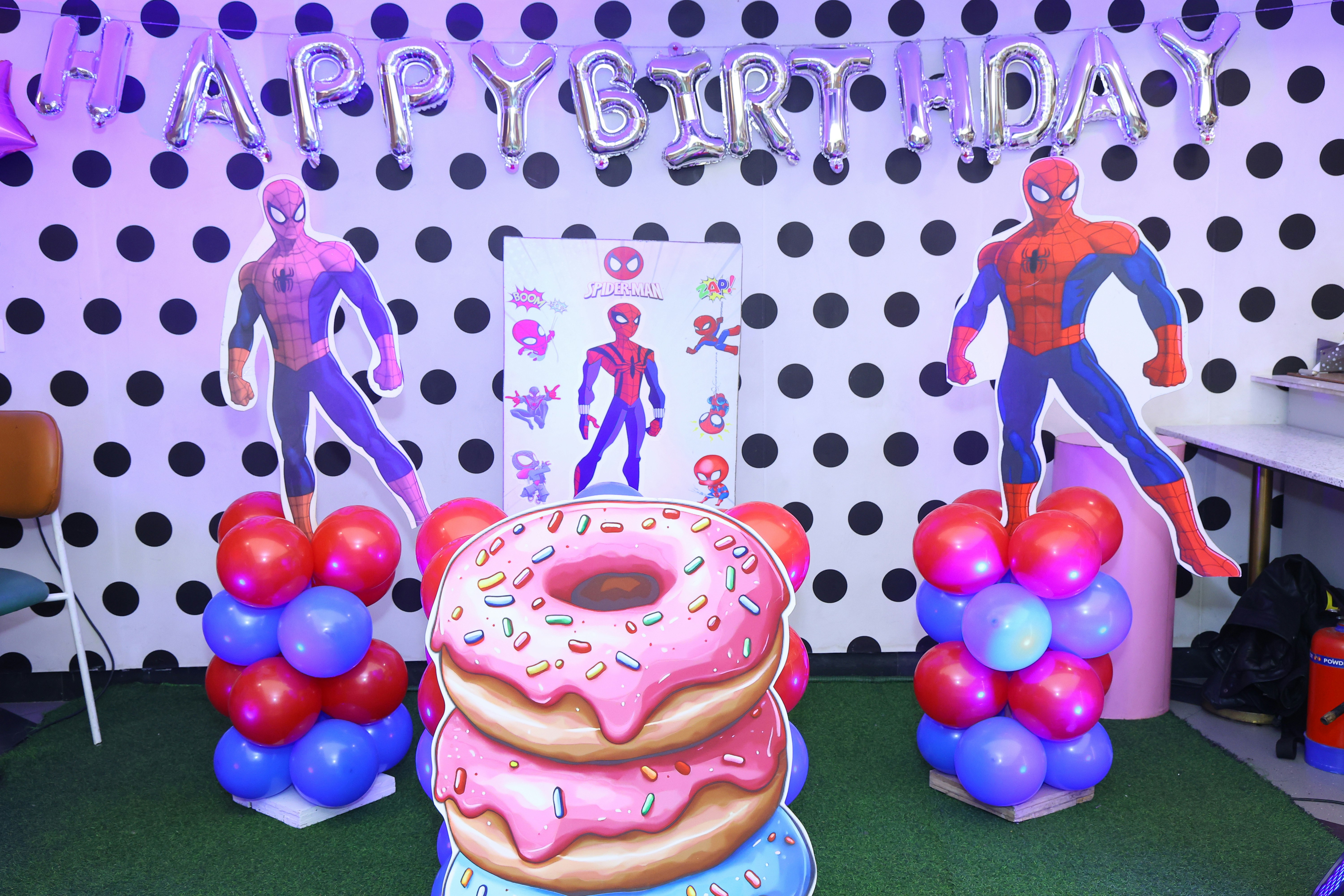 Spider-man themed birthday party decorations with donuts and balloons