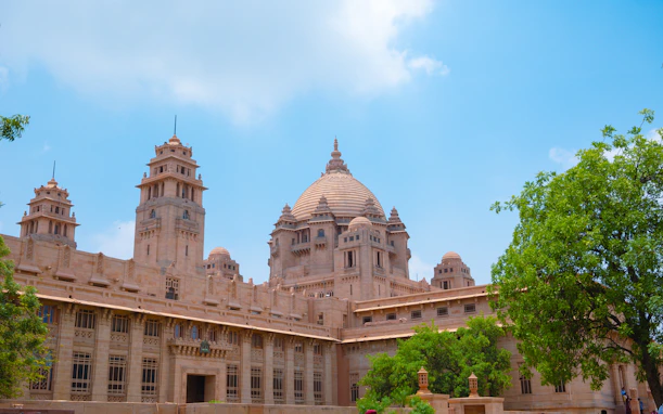 A grand sandstone palace with domed towers under blue sky.