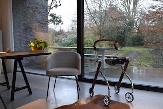A walker and chair by a large window.