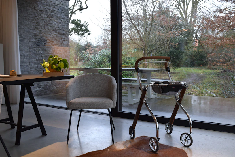 A walker and chair by a large window.