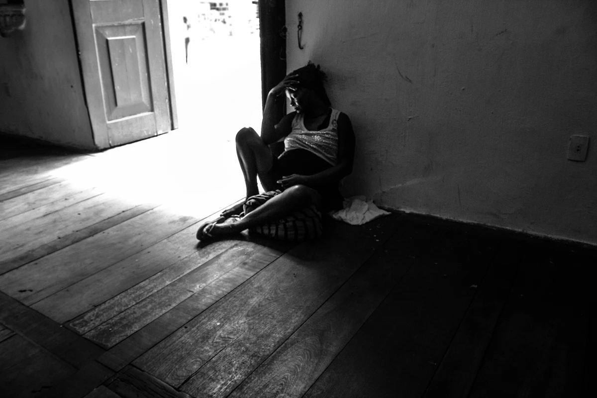 Person sitting alone in a dimly lit room, representing the physical heaviness of depression