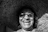 A smiling woman wearing a large straw hat and sunglasses.
