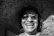 A smiling woman wearing a large straw hat and sunglasses.