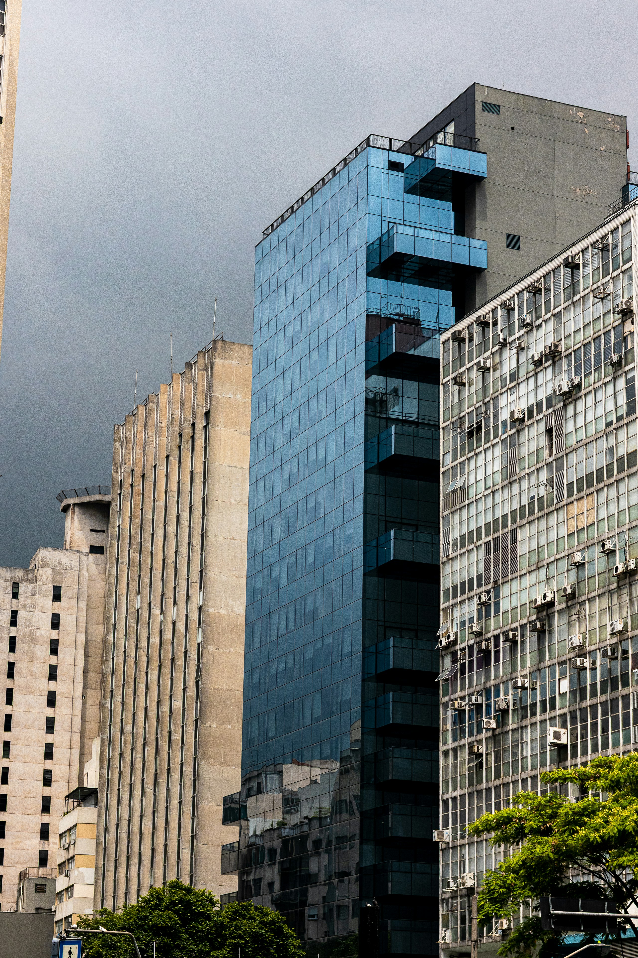 Modern glass building among older concrete structures.