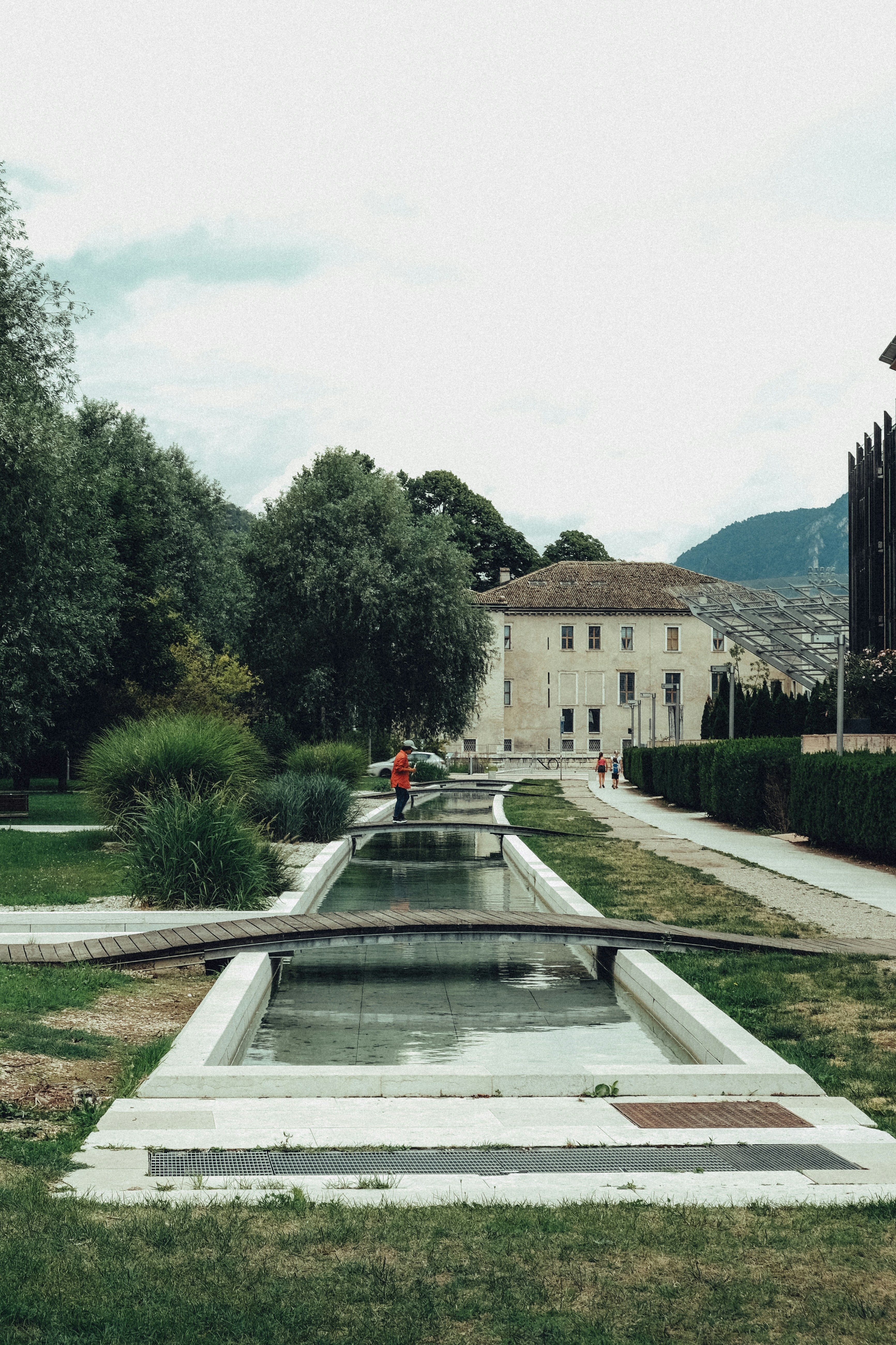 A person in an orange jacket walks by water channels.