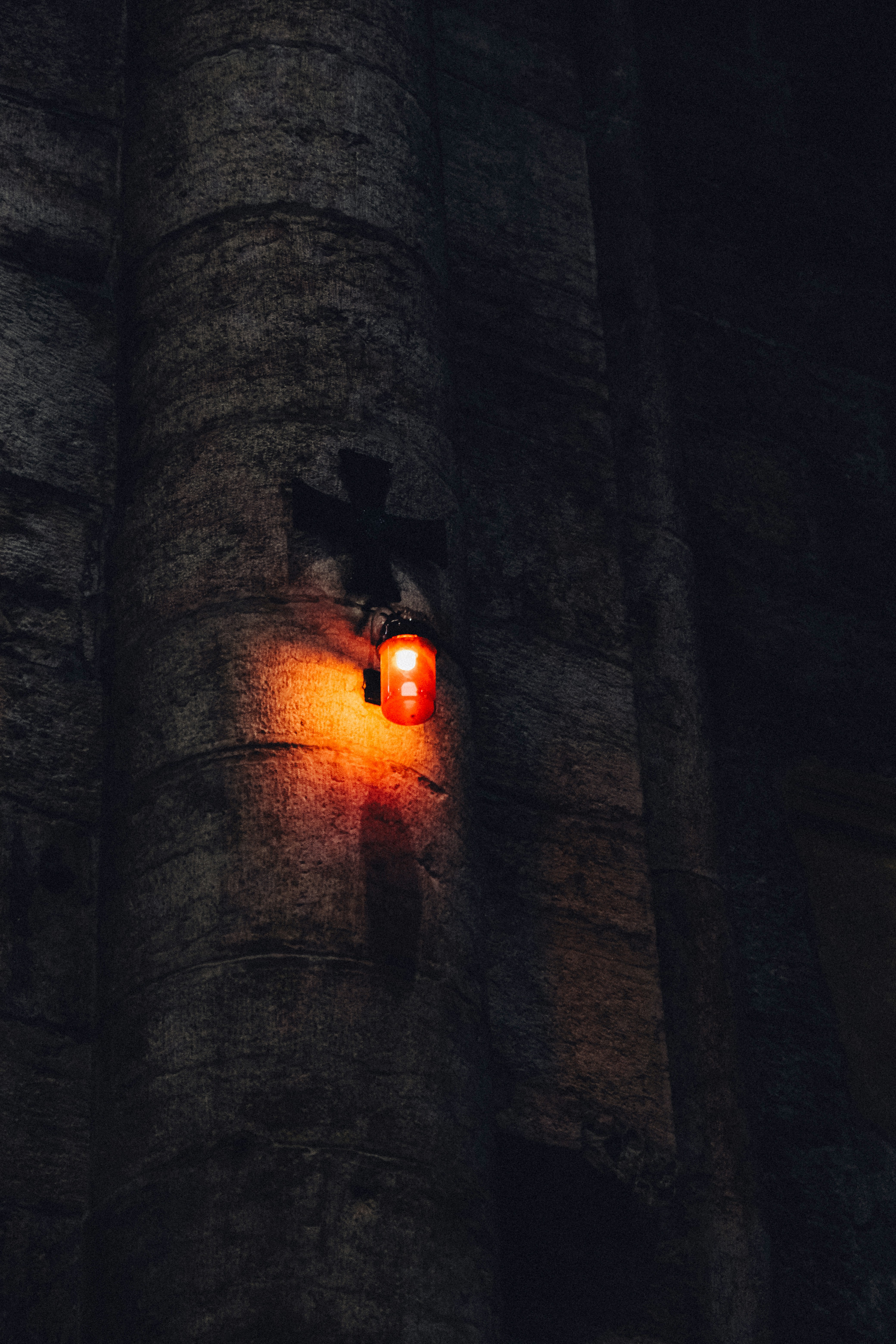 A single red lantern hangs on a stone wall.