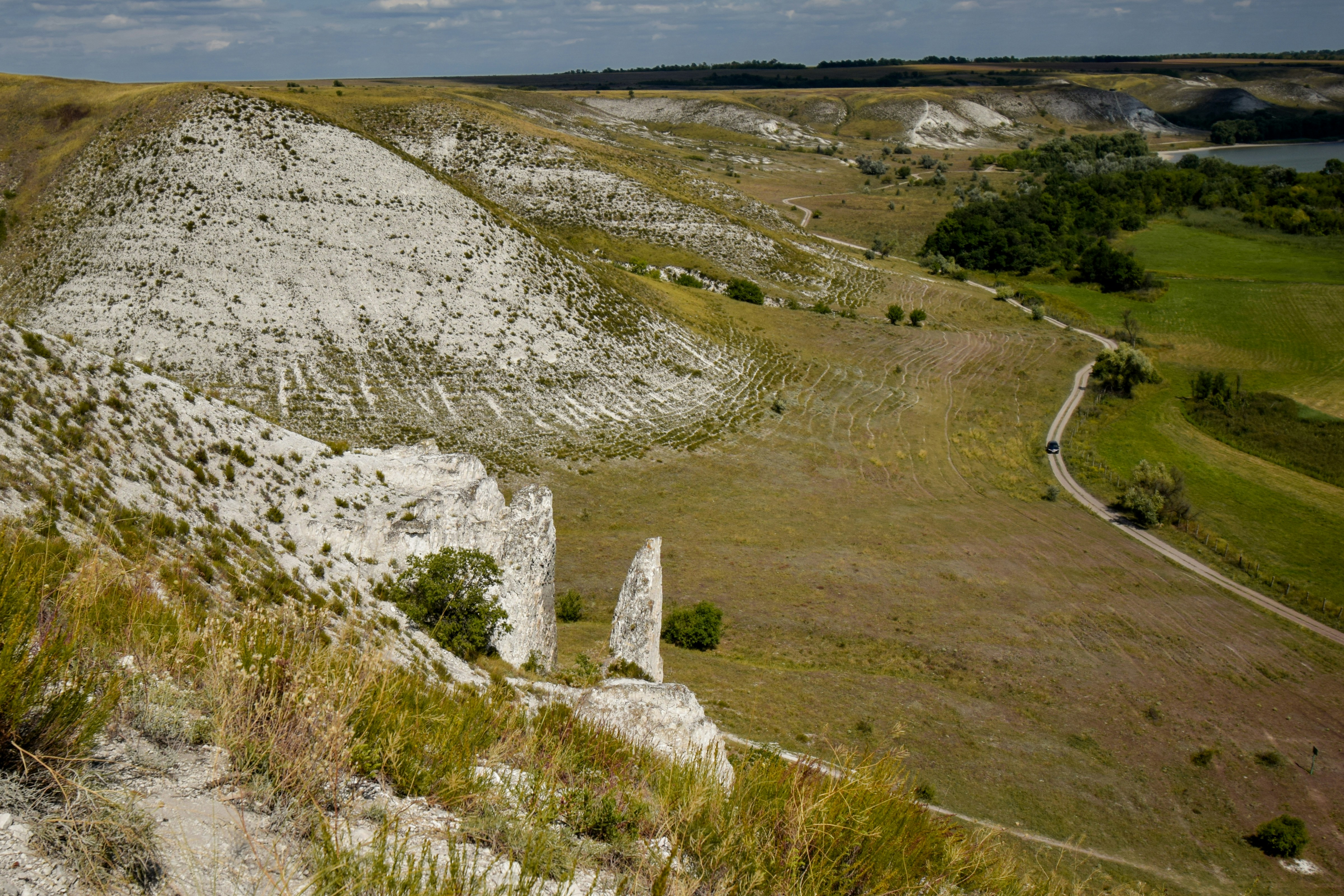 Colinas rochosas brancas com campos verdes e um rio.