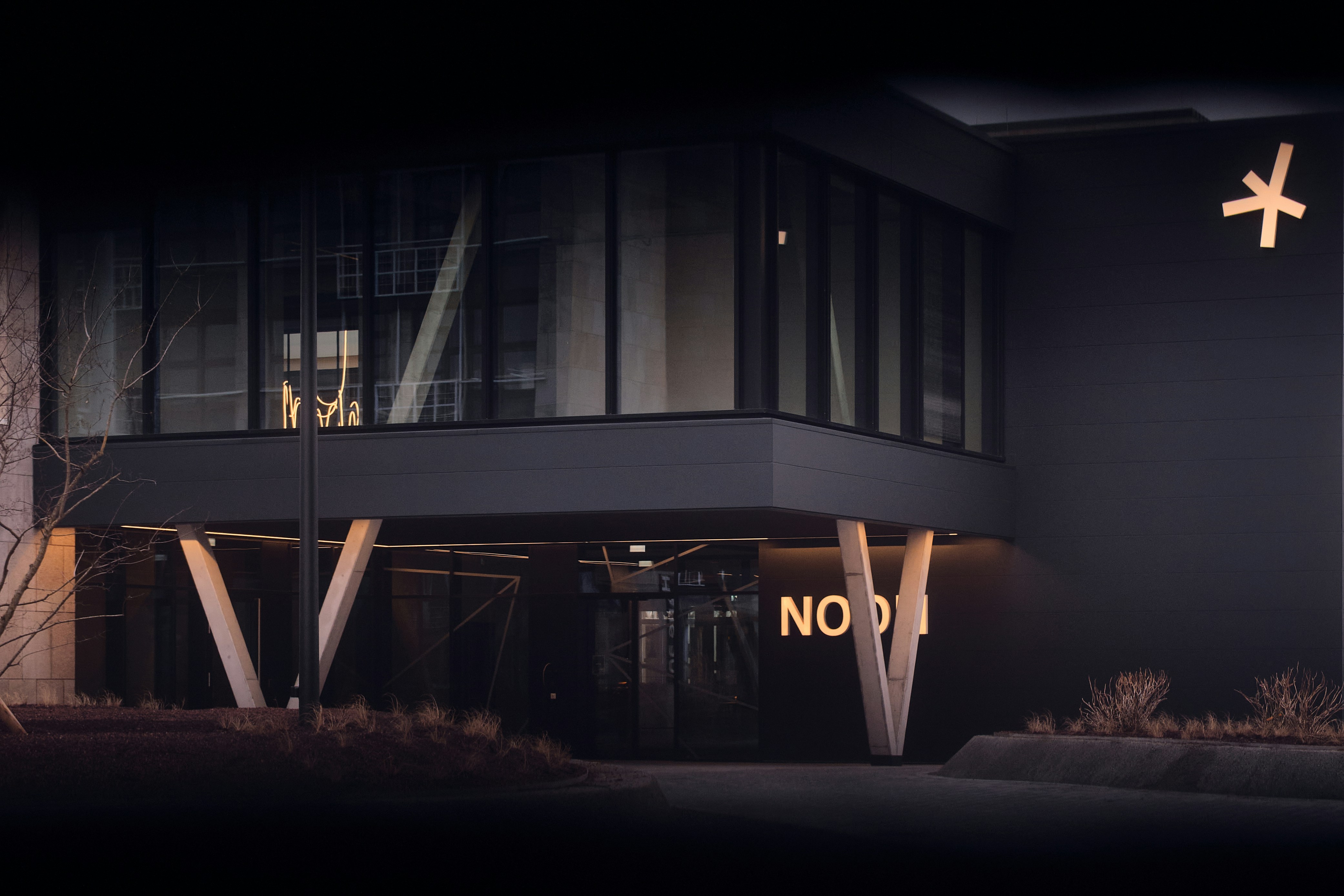 Modern building entrance at night with illuminated sign.