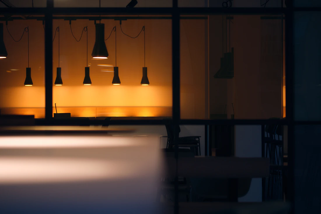 A modern office interior lit by pendant lights at night