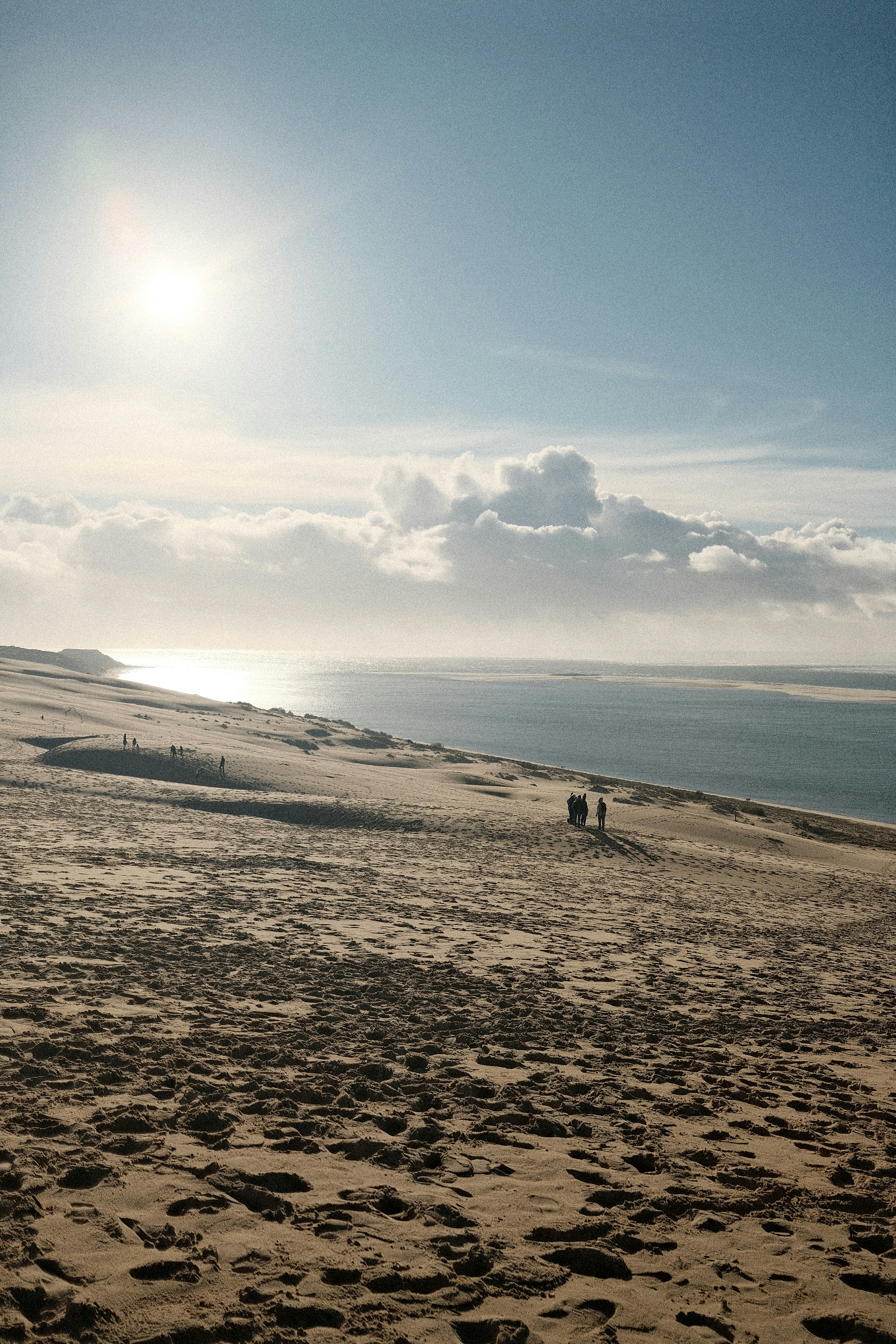 Menschen, die auf einer Sanddüne mit Blick auf den Ozean spazieren gehen