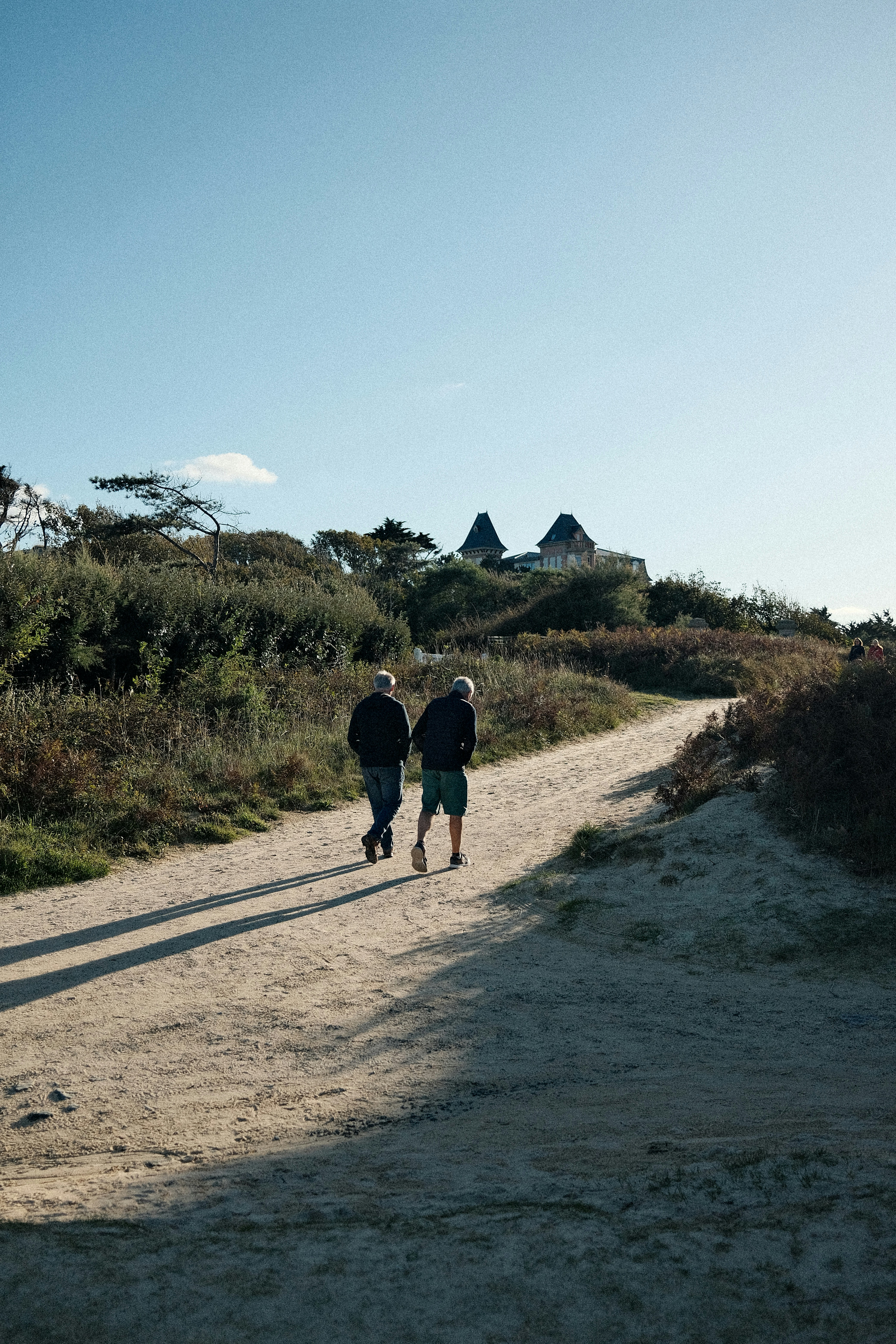 Zwei Menschen gehen auf einem Weg zu fernen Ruinen.