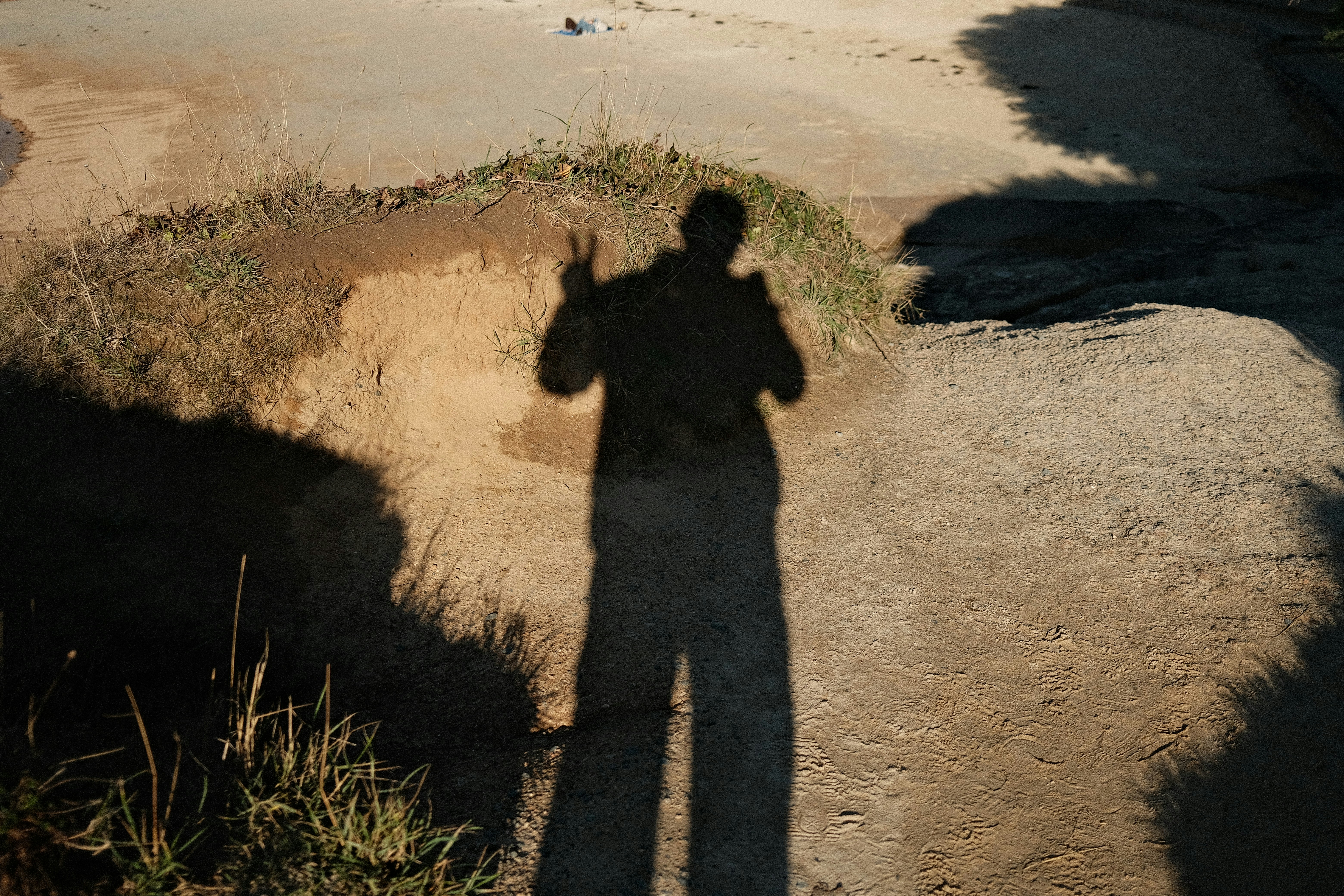 Shadow of a person making peace sign on ground