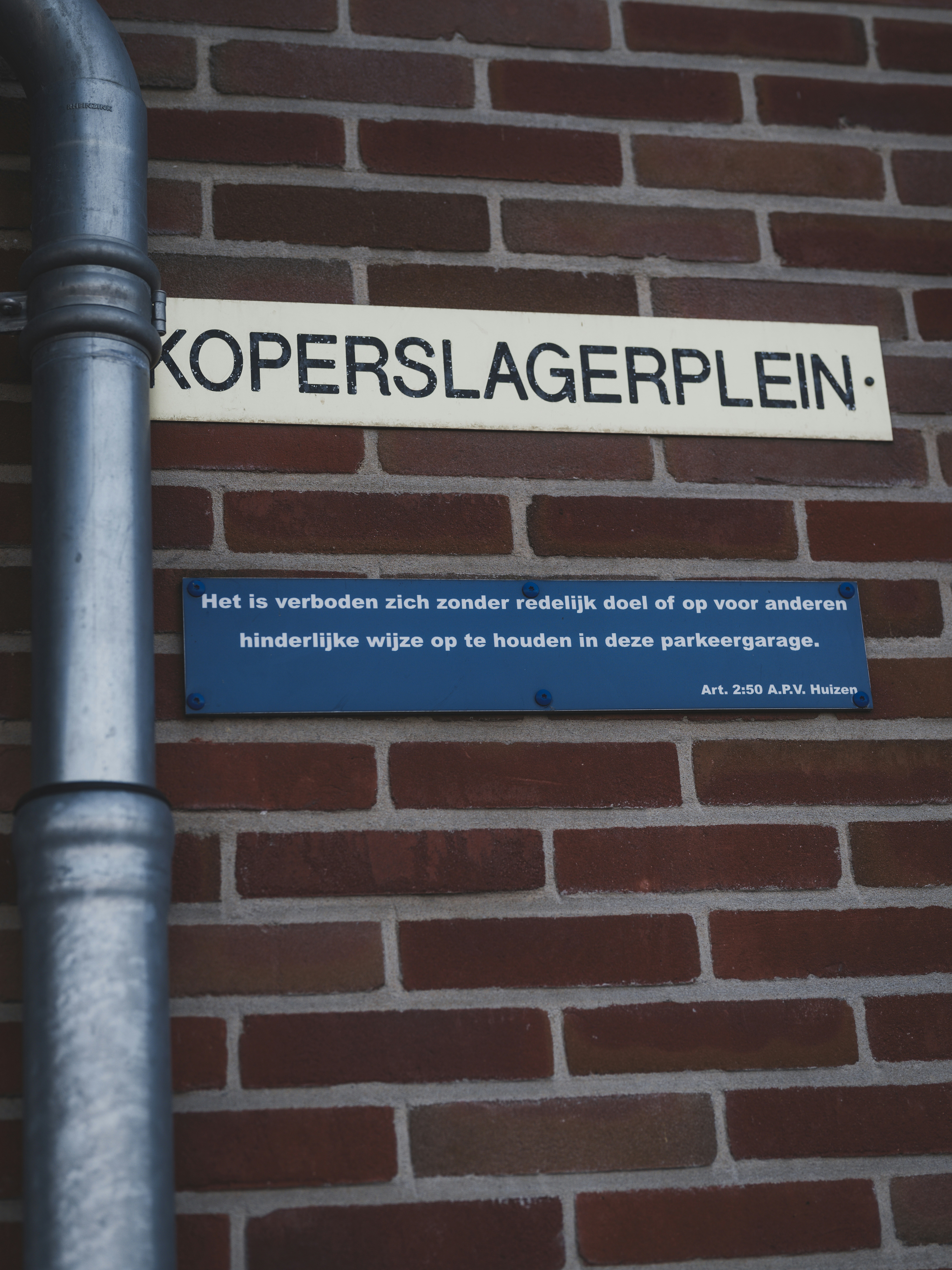 Street sign on brick wall with pipe