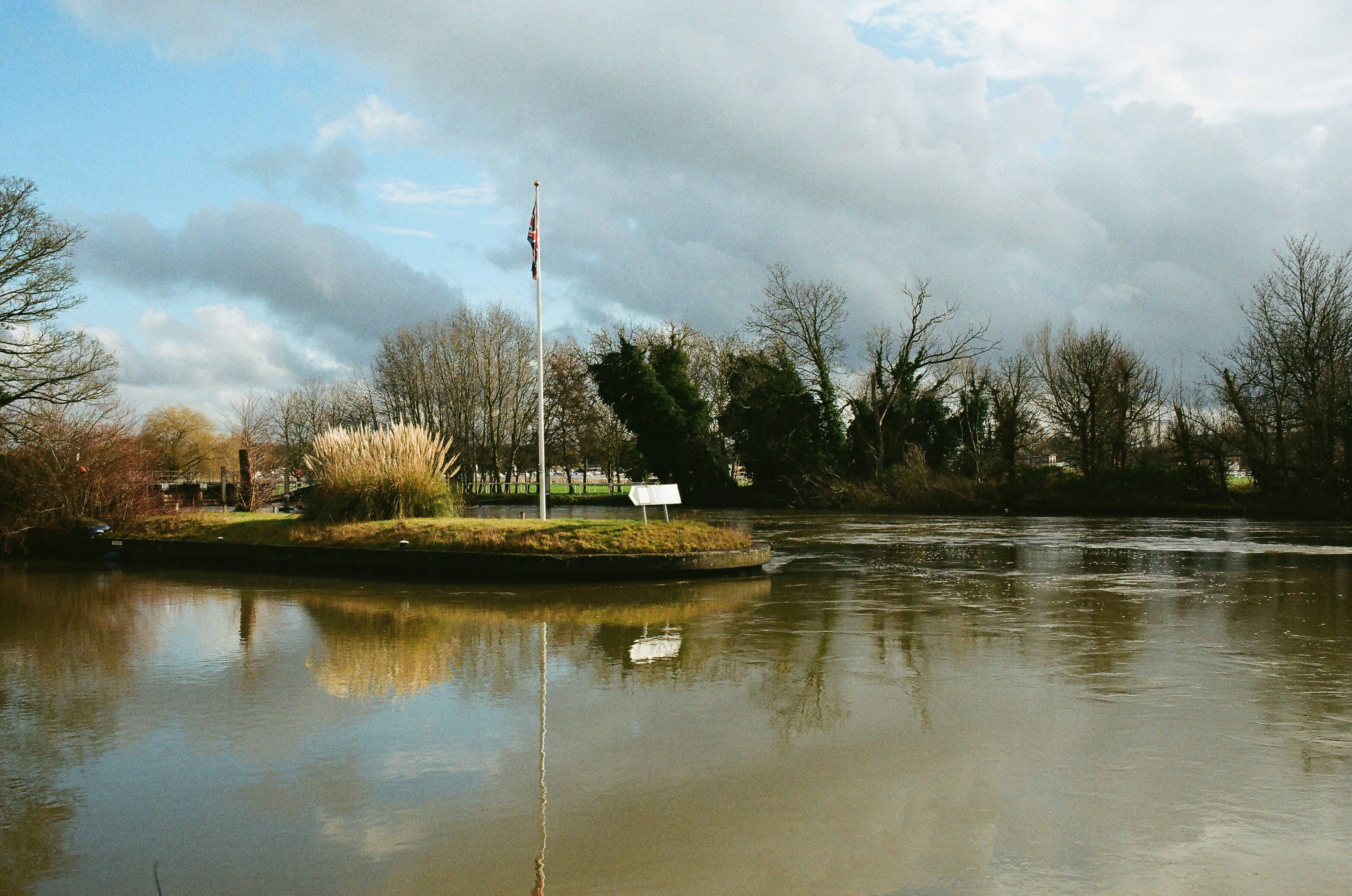 A small island with a flagpole in a calm river.