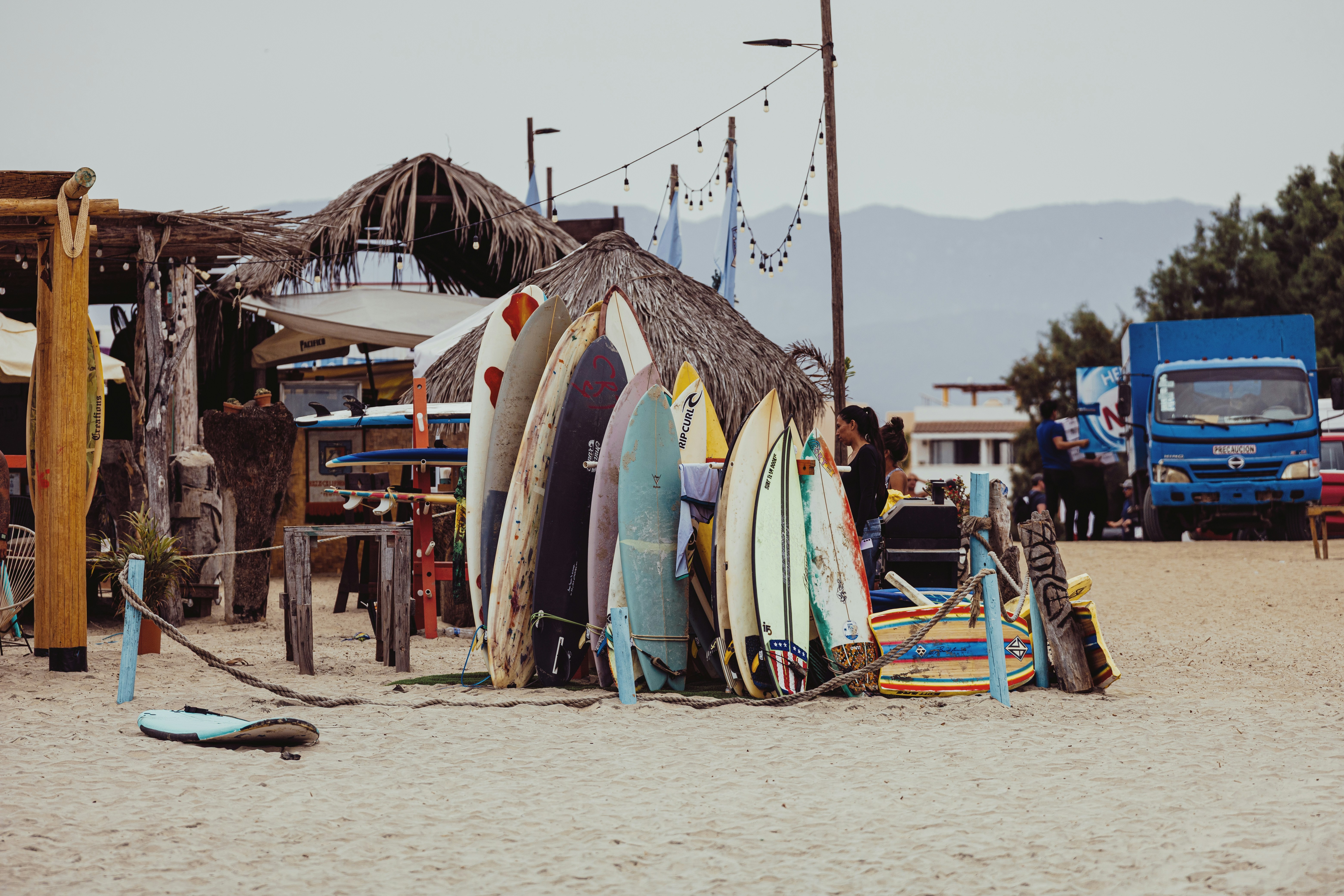 Surfbretter, die an einer strohgedeckten Hütte am Strand lehnen.