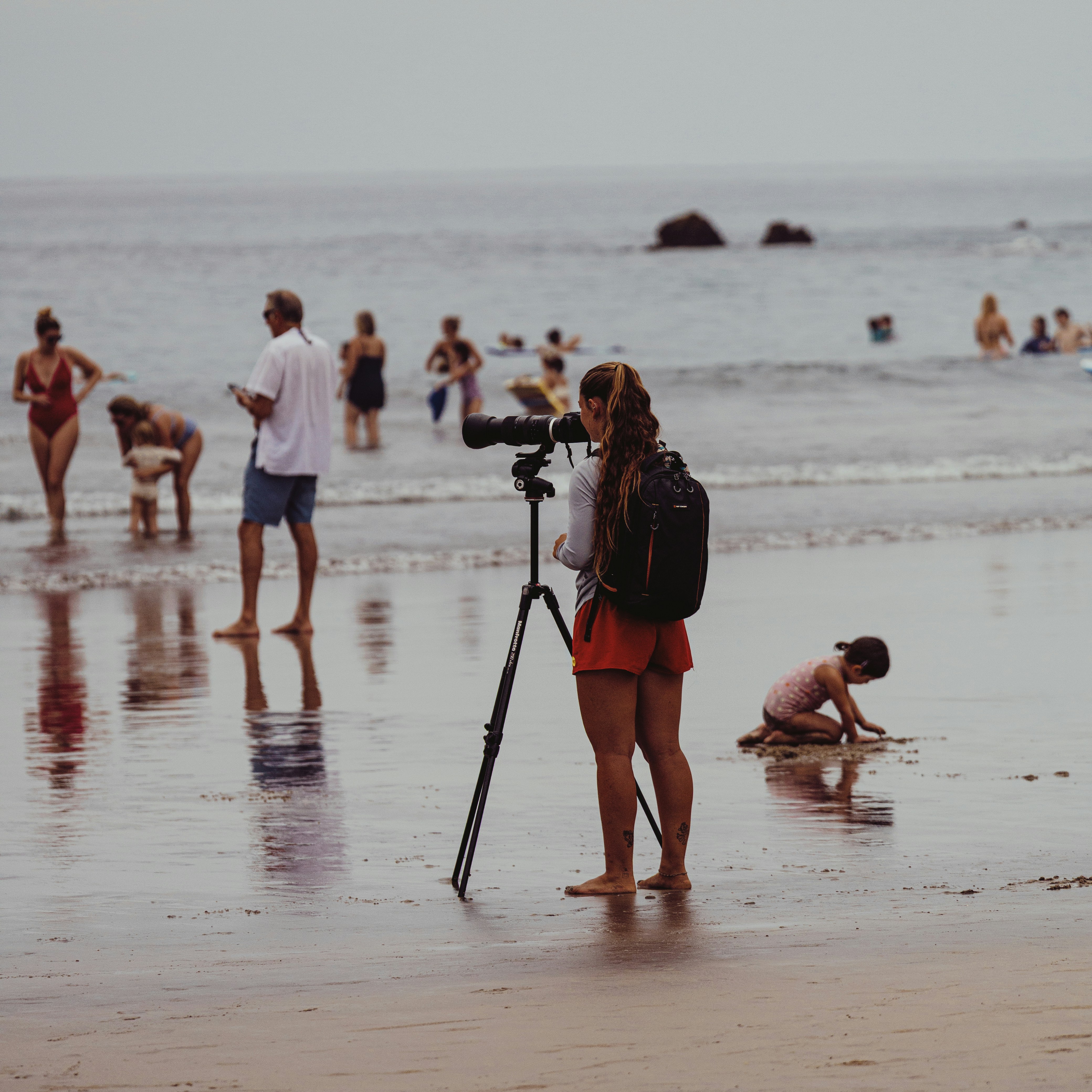 Frau mit Kamera auf Stativ am Strand