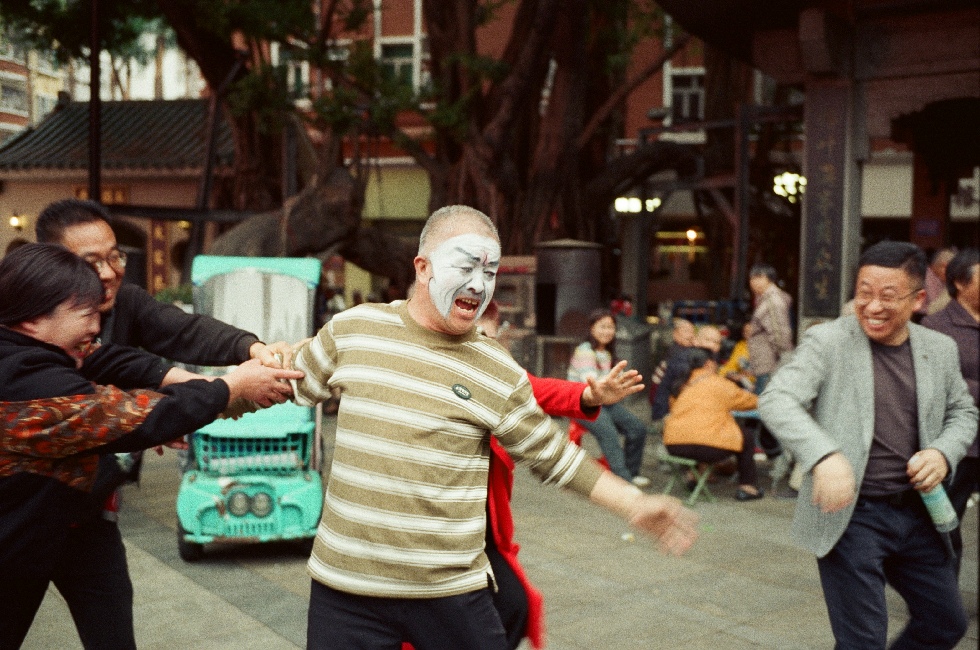 Man with clown makeup being pulled by group