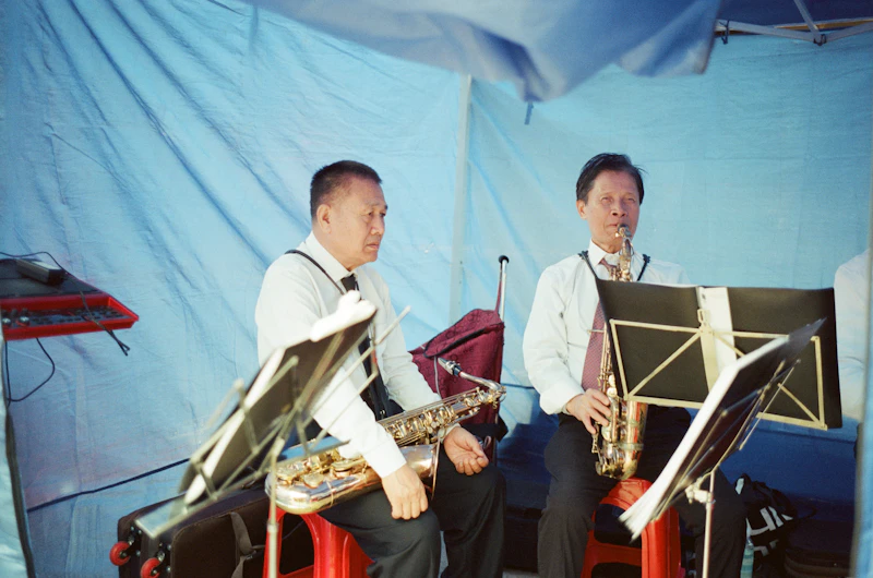 Two musicians playing saxophones together at an outdoor tented performance (generic jazz-performance photo, not verifiably the Chicago Jazz Festival)