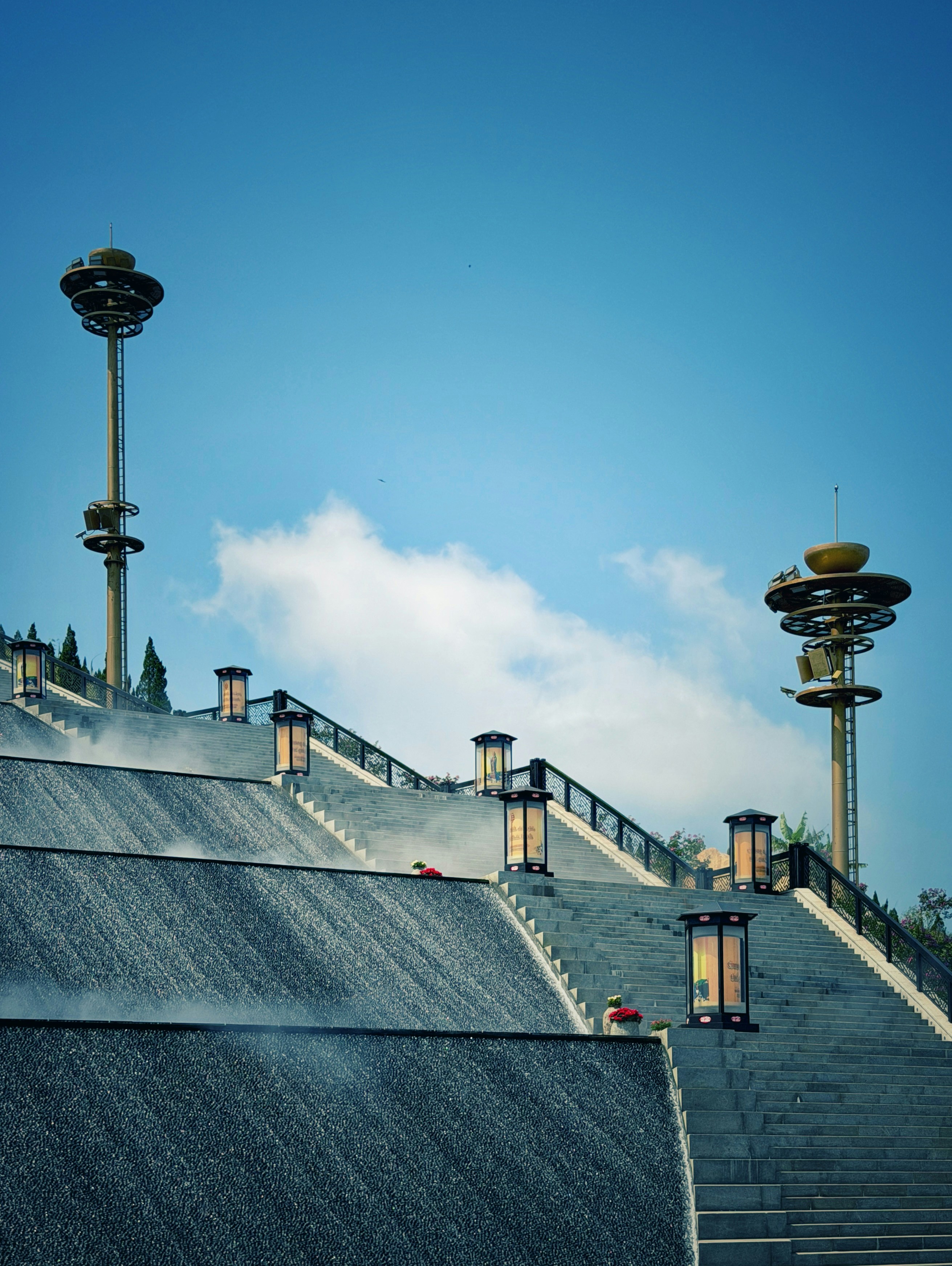 Grand staircase with cascading water and tall lamps.