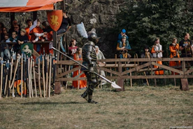 Knight in armor walks with a polearm at a festival