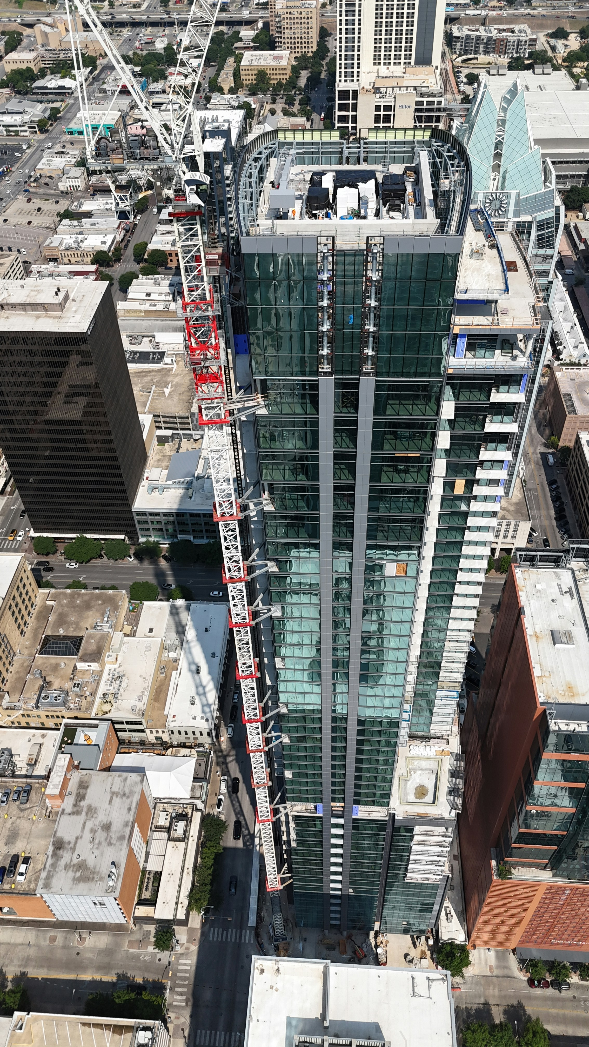 Construction crane attached to a tall glass skyscraper.