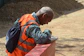 Man in orange vest writing on paper outdoors