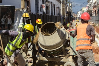 Construction workers operating a cement mixer on a street.