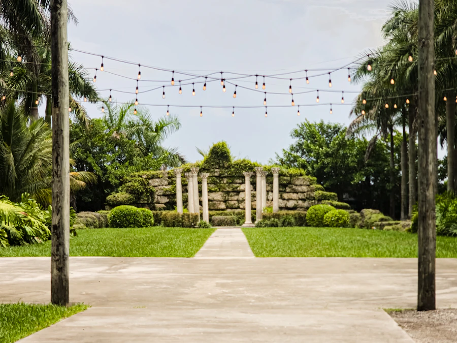 Garden pathway with string lights leading through stone archways at an outdoor event venue