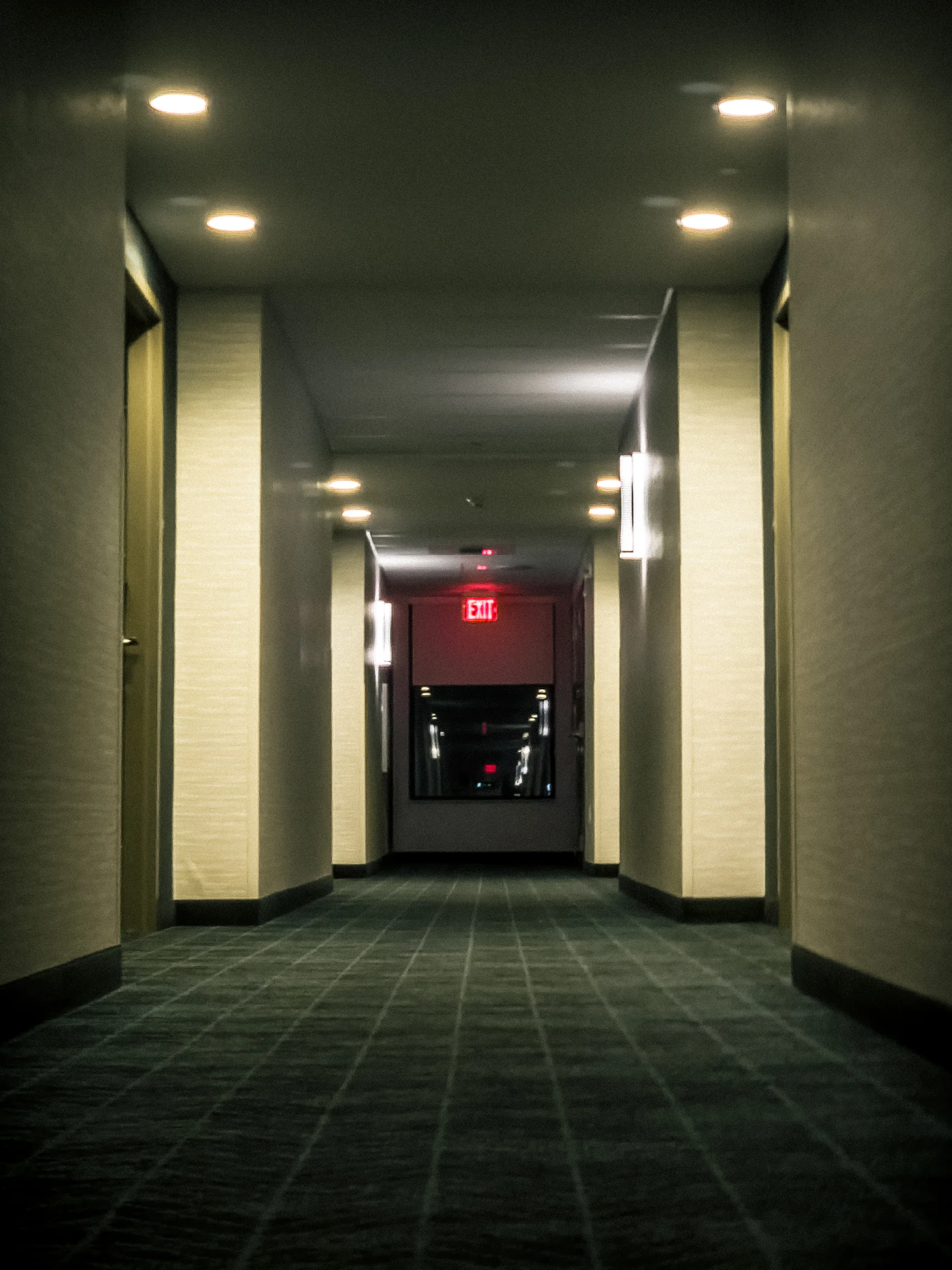 A dim hotel corridor at night, where a guest-technology fault is noticed first