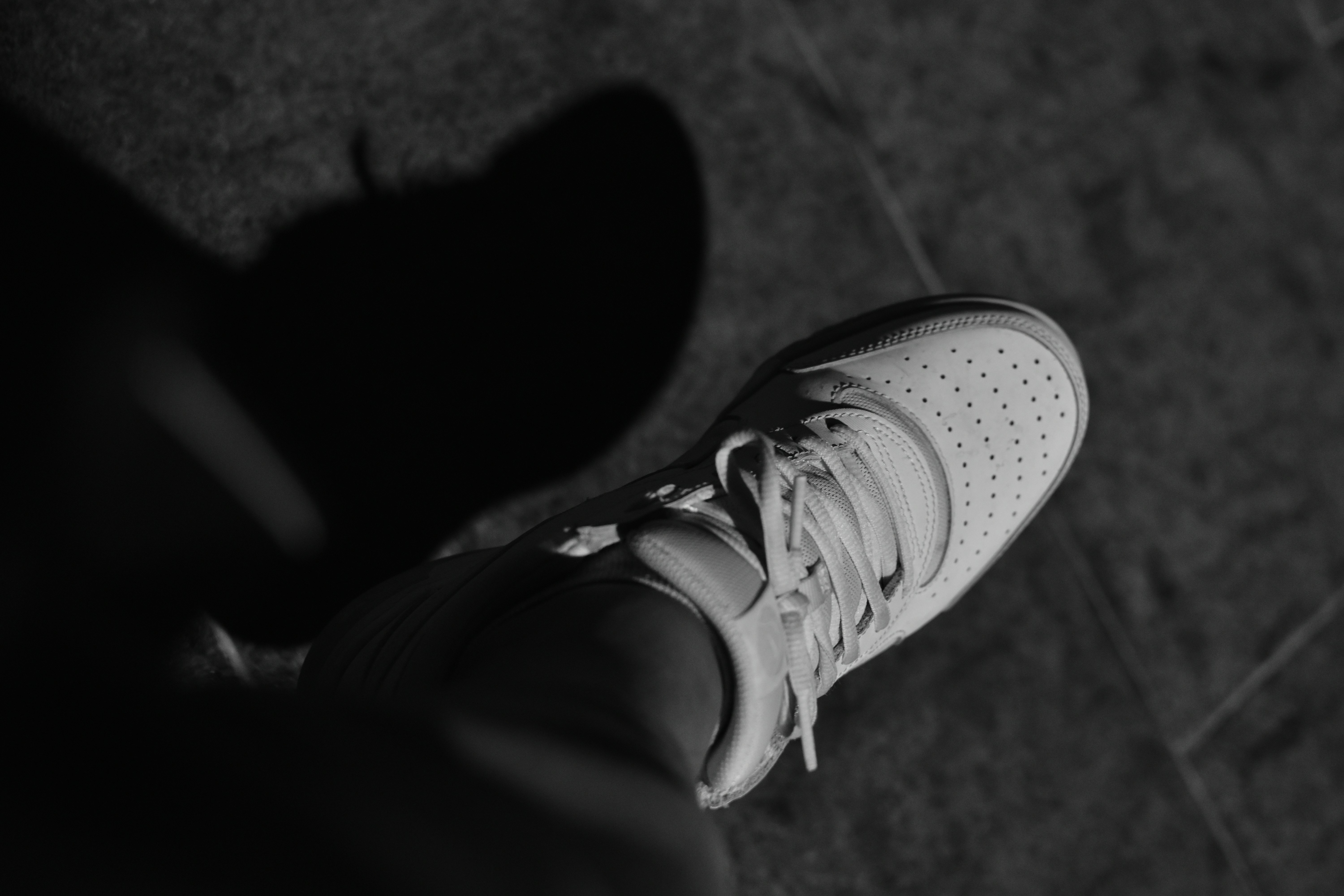 A person's white sneaker casts a shadow.