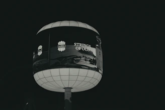 A spherical billboard advertising "strings of old" at night.