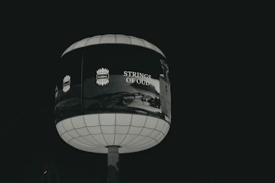 A spherical billboard advertising "strings of old" at night.