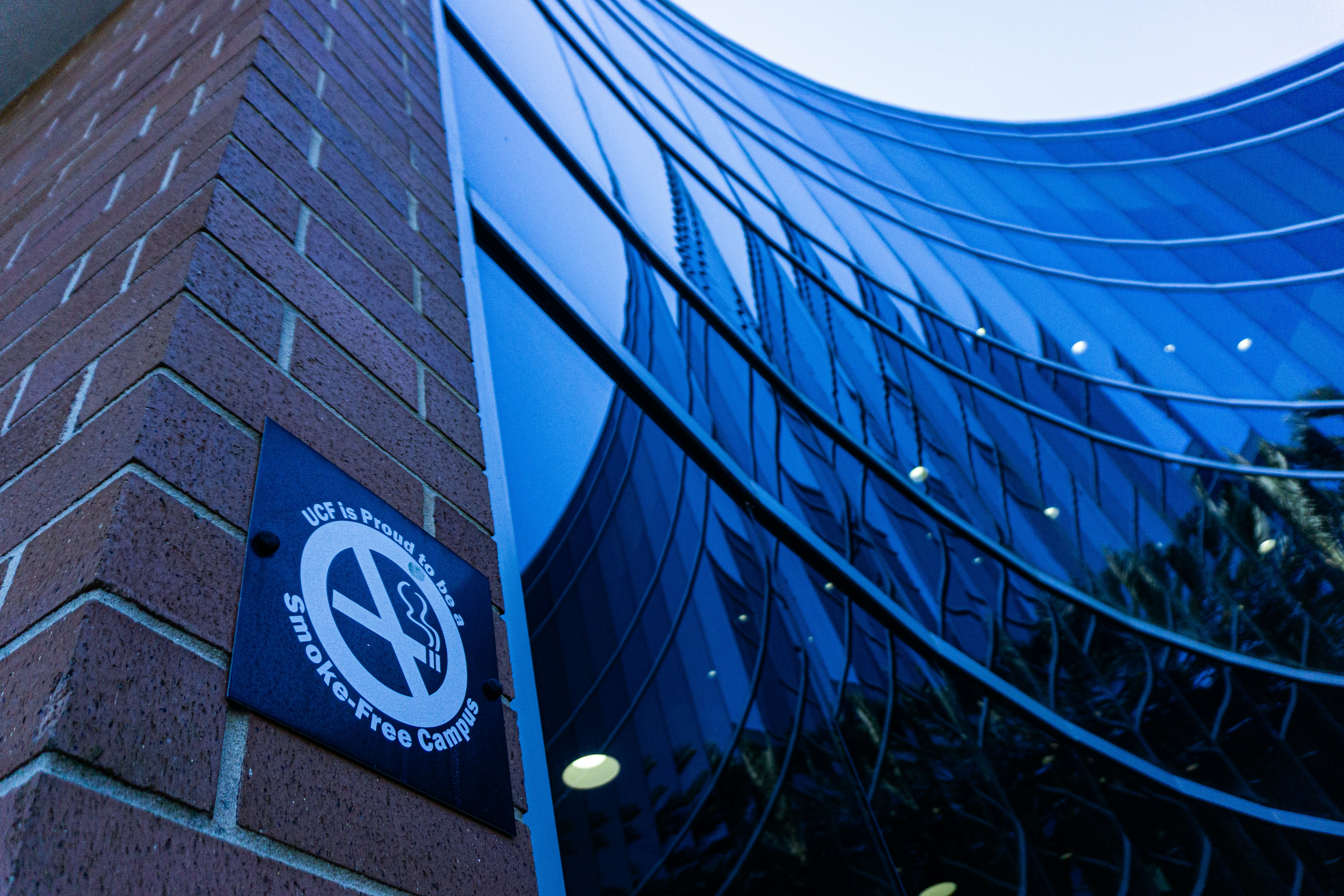No smoking sign on brick wall next to glass building