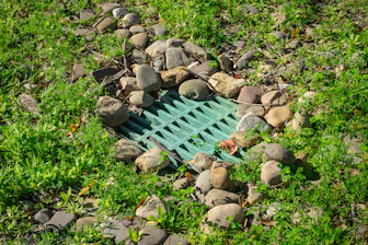 Green grate surrounded by rocks and grass