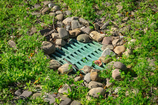 Green grate surrounded by rocks and grass