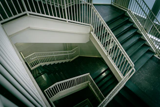 Modern staircase with white railings descends downwards.