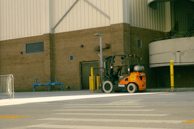 Orange forklift parked outside industrial building