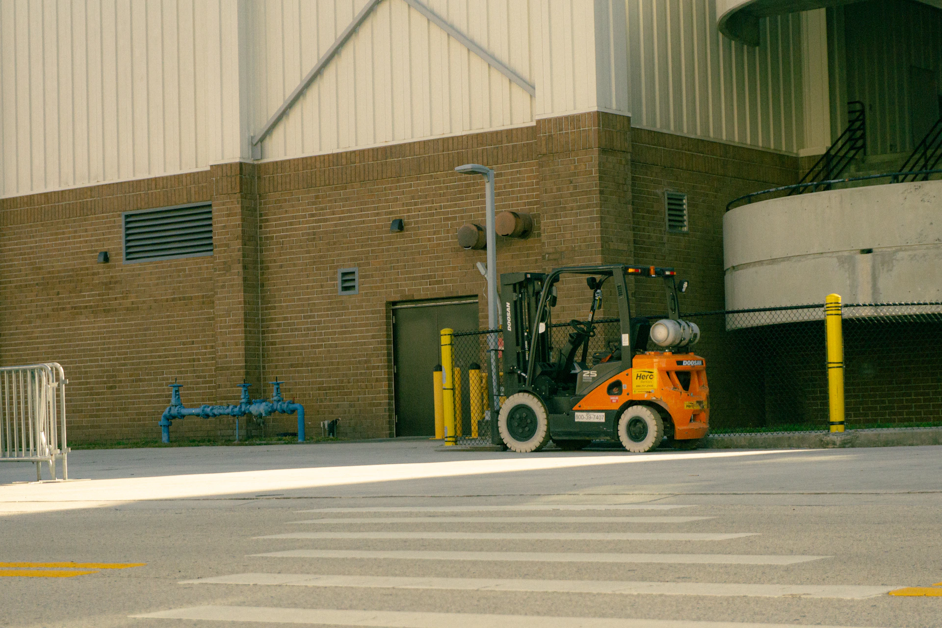 Orange forklift parked outside industrial building