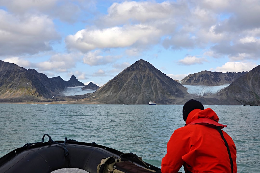 Person in red jacket on boat with arctic mountains