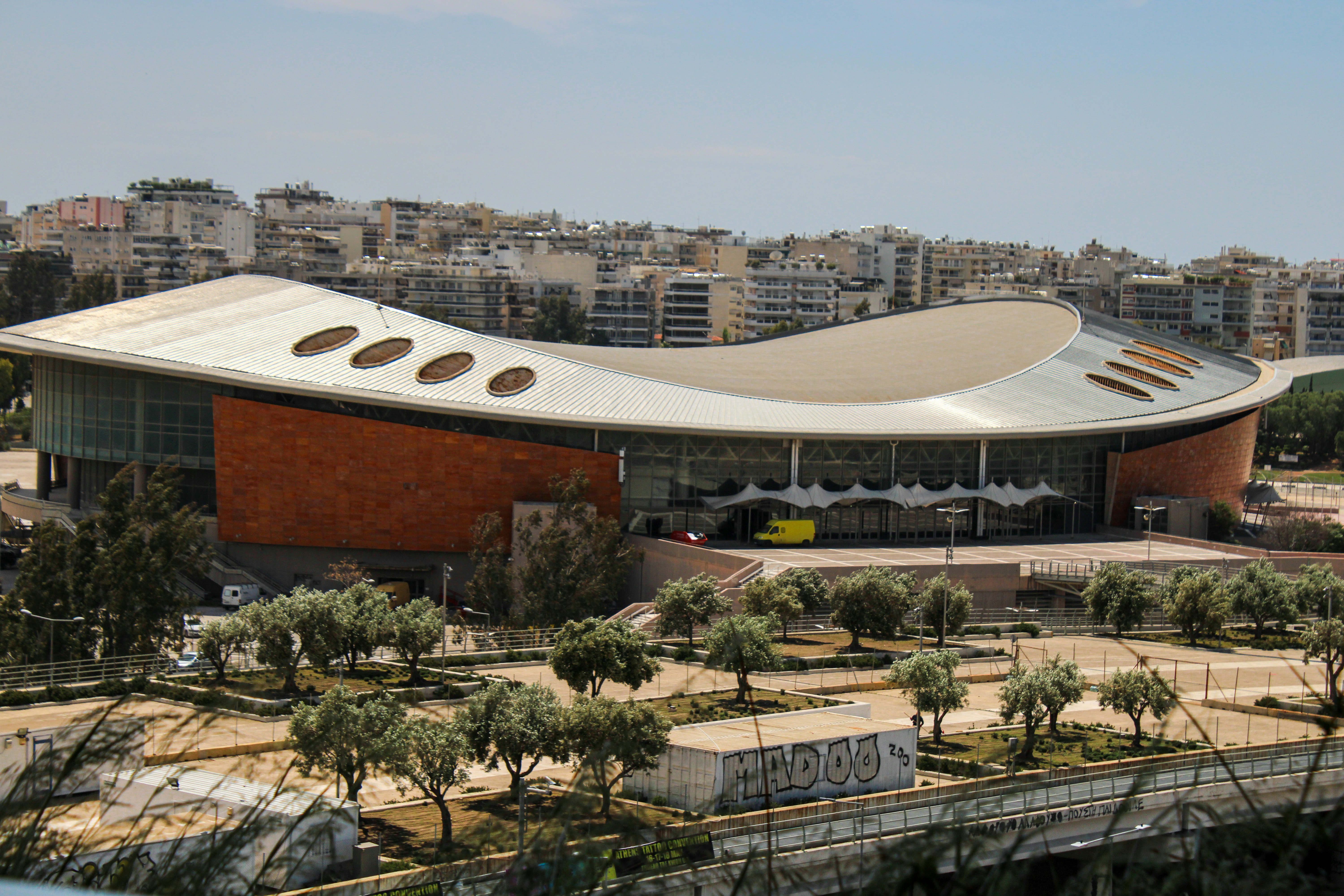 Modern building with curved roof and surrounding trees.